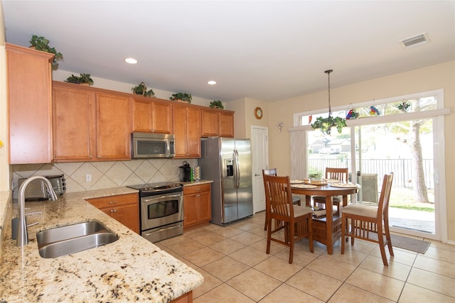 kitchen featuring light stone countertops, stainless steel appliances, sink, pendant lighting, and light tile patterned floors