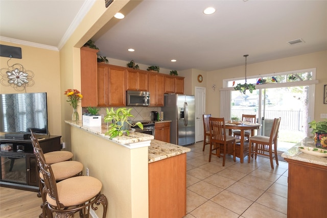 kitchen with light stone countertops, appliances with stainless steel finishes, kitchen peninsula, tasteful backsplash, and pendant lighting