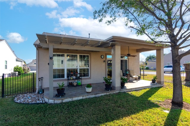 rear view of property featuring ceiling fan, a yard, and a patio