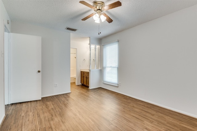 unfurnished bedroom with ensuite bath, ceiling fan, light hardwood / wood-style floors, and a textured ceiling