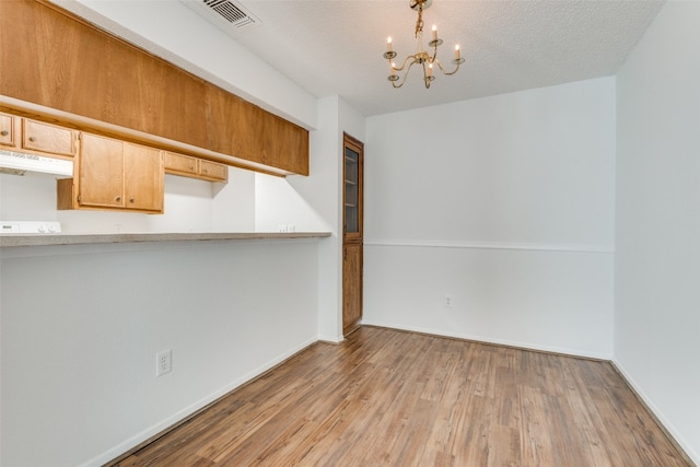 interior space with a textured ceiling, an inviting chandelier, and light hardwood / wood-style flooring