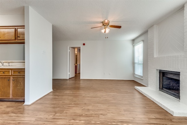 unfurnished living room featuring a fireplace, light hardwood / wood-style flooring, and a textured ceiling