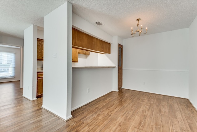 interior space featuring an inviting chandelier, light hardwood / wood-style floors, and a textured ceiling