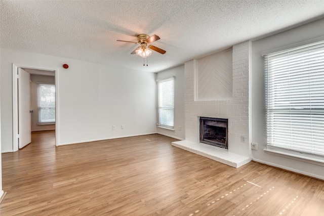 unfurnished living room with ceiling fan, light hardwood / wood-style floors, a wealth of natural light, and a textured ceiling