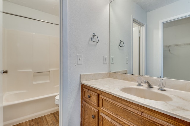 full bathroom featuring toilet, shower / washtub combination, hardwood / wood-style flooring, vanity, and a textured ceiling