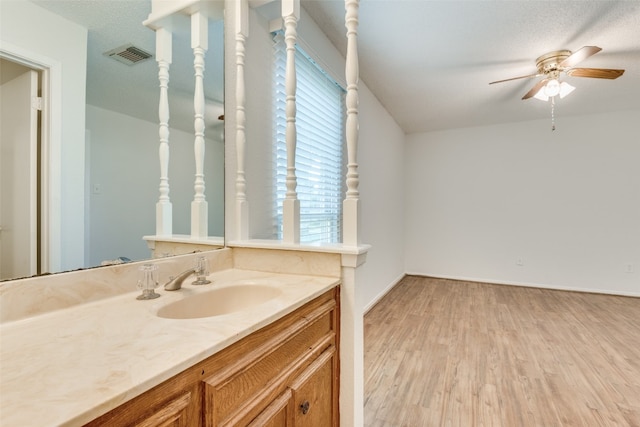 bathroom with ceiling fan, vanity, hardwood / wood-style floors, and a textured ceiling