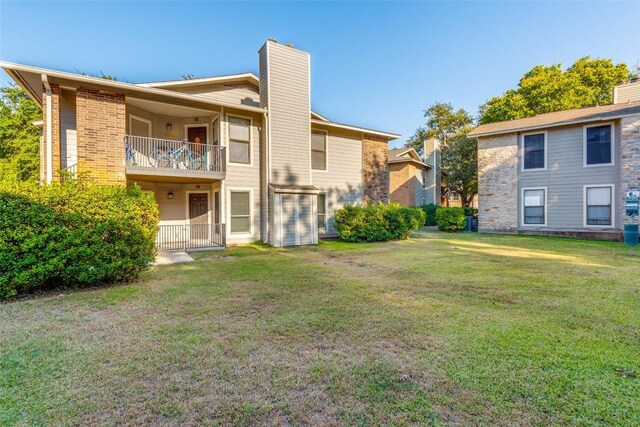 10616 Mellow Mdws Unit 9D, Austin, TX 78750 - back of house with brick siding, a yard, a chimney, and a balcony
