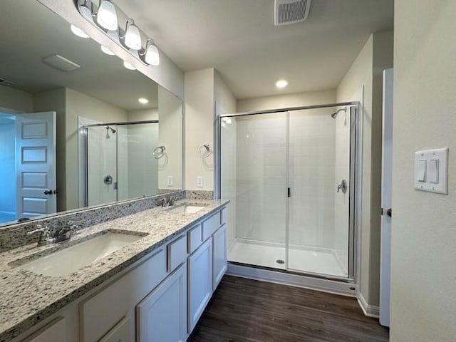 full bathroom with double vanity, visible vents, a sink, and wood finished floors