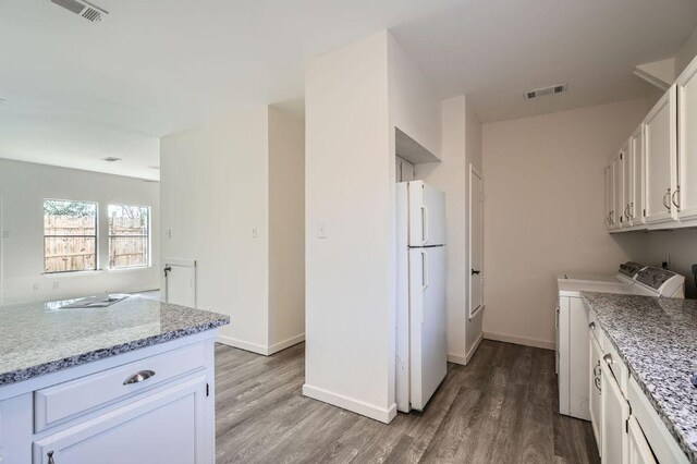 109 W Mockingbird Ln Unit A2, Austin, TX 78745 - kitchen with freestanding refrigerator, washer and clothes dryer, light wood-type flooring, and white cabinetry