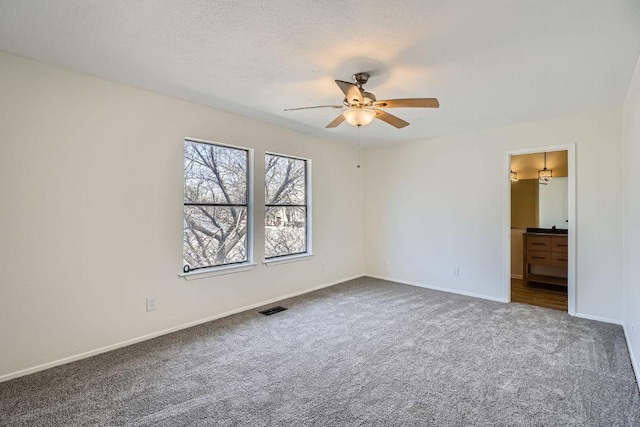 unfurnished bedroom with a textured ceiling, carpet flooring, visible vents, and baseboards