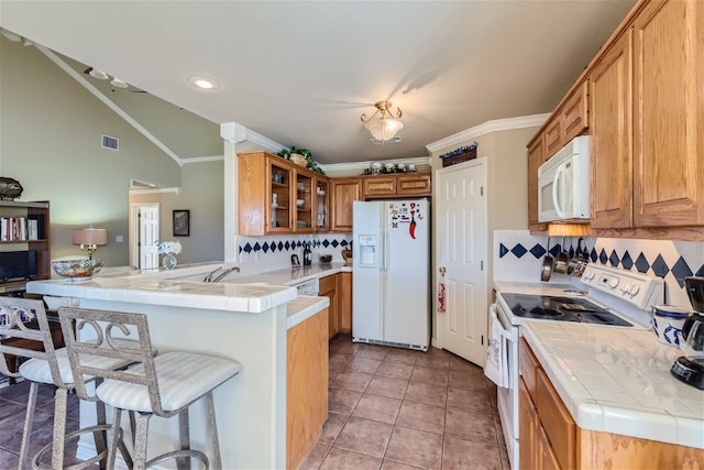 kitchen with tile counters, kitchen peninsula, white appliances, and ornamental molding