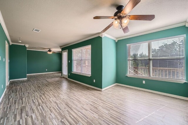 empty room with a textured ceiling, ornamental molding, and hardwood / wood-style flooring