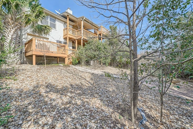 back of house with a wooden deck and a balcony