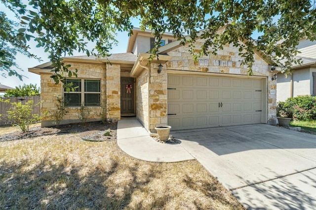 view of front of house featuring a garage, driveway, stone siding, and fence