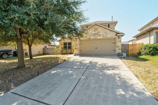 traditional home with stone siding, concrete driveway, fence, an attached garage, and a front yard