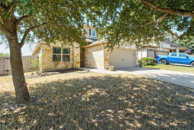 view of property hidden behind natural elements with concrete driveway, an attached garage, fence, and stone siding