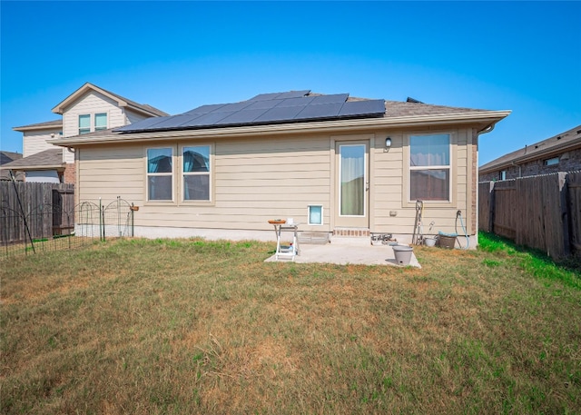 back of house featuring solar panels, a lawn, and a patio area