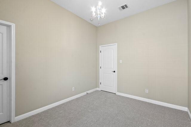 carpeted empty room with a chandelier