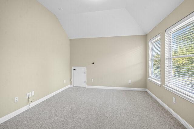 carpeted empty room with lofted ceiling