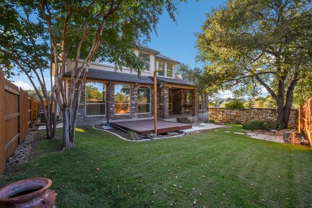 back of property featuring a wooden deck and a yard