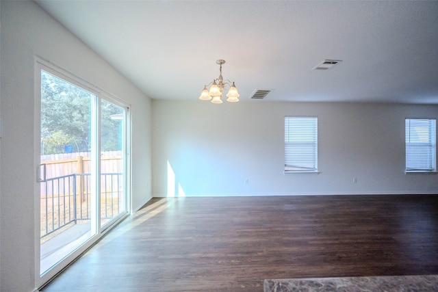 empty room featuring an inviting chandelier and wood-type flooring