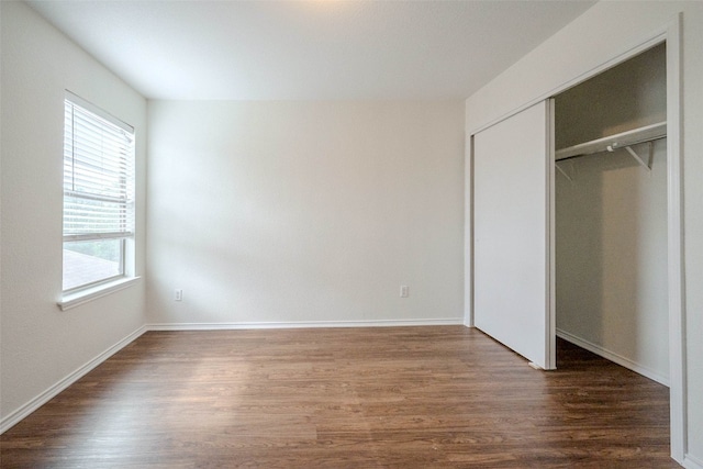 unfurnished bedroom featuring a closet and dark wood-type flooring