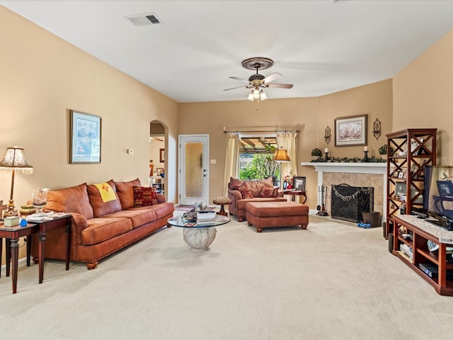 carpeted living room with a tiled fireplace and ceiling fan