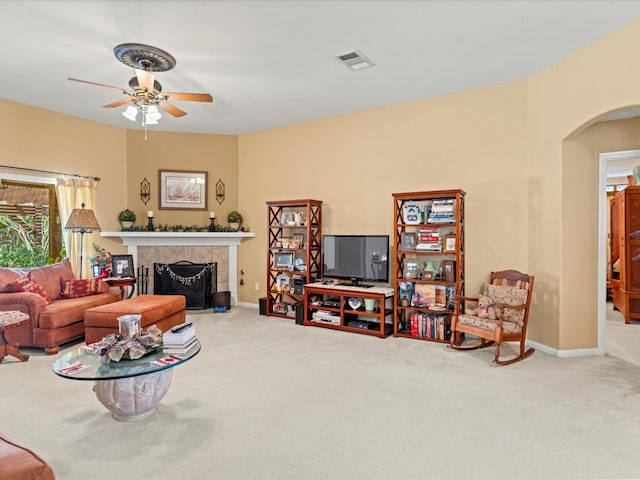 carpeted living room featuring a tile fireplace and ceiling fan