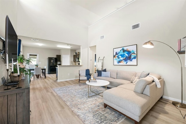 living room with a high ceiling and light wood-type flooring