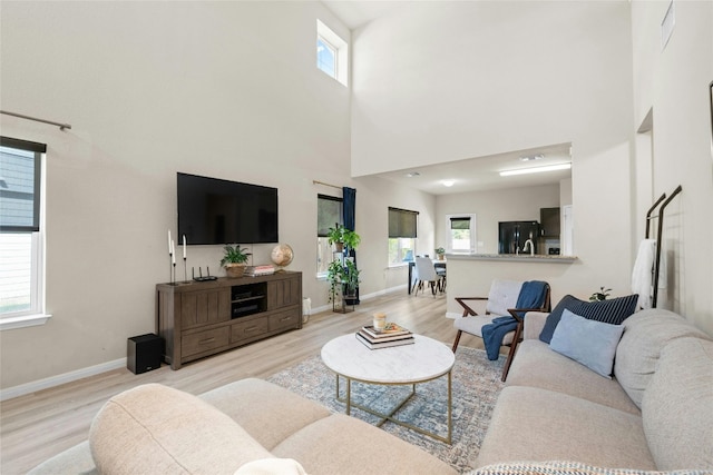 living room with light hardwood / wood-style floors, a high ceiling, and plenty of natural light