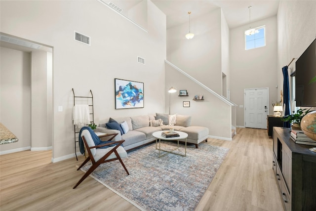 living room with light hardwood / wood-style floors and a towering ceiling