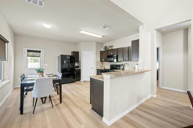 kitchen featuring dark brown cabinets, black appliances, light wood-type flooring, and light stone counters