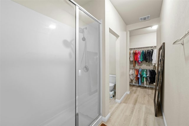 bathroom featuring a shower with door, toilet, and hardwood / wood-style flooring