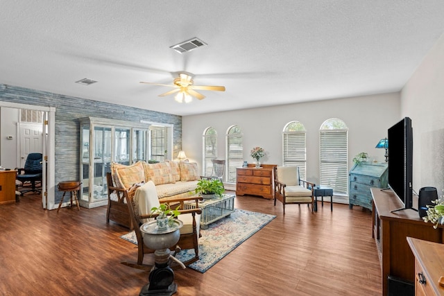 living room featuring a textured ceiling, hardwood / wood-style flooring, and ceiling fan