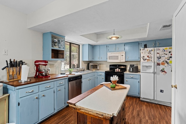 kitchen with blue cabinetry, dark hardwood / wood-style flooring, a raised ceiling, and white appliances