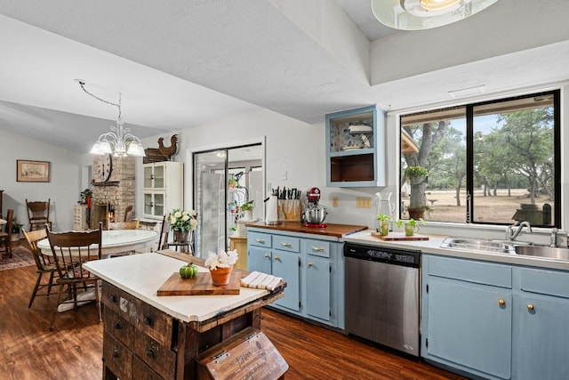 kitchen with dishwasher, blue cabinets, a fireplace, and dark hardwood / wood-style floors