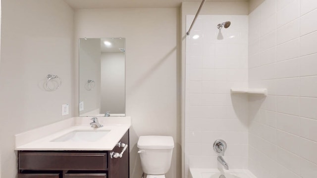 full bathroom featuring tiled shower / bath, vanity, and toilet