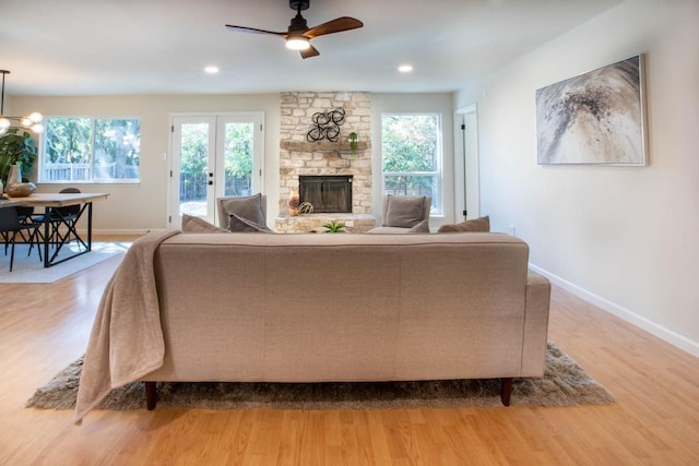 living room featuring ceiling fan, a healthy amount of sunlight, a fireplace, and light hardwood / wood-style floors