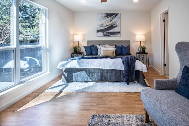 bedroom with multiple windows, wood-type flooring, and ceiling fan