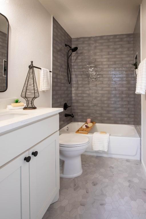 full bathroom featuring tiled shower / bath combo, vanity, and toilet