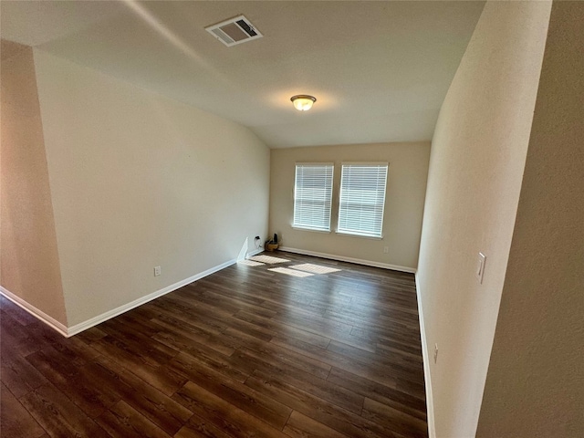 spare room with dark hardwood / wood-style flooring and vaulted ceiling