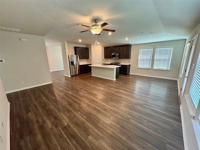 unfurnished living room featuring dark wood-type flooring, ceiling fan, sink, and plenty of natural light