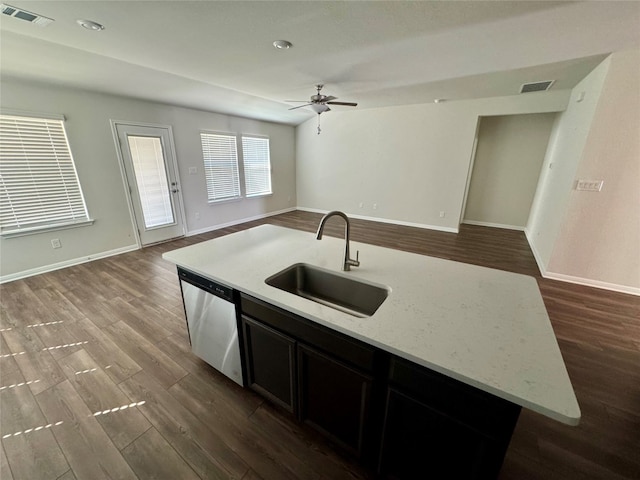 kitchen with an island with sink, light stone countertops, wood-type flooring, dishwasher, and sink