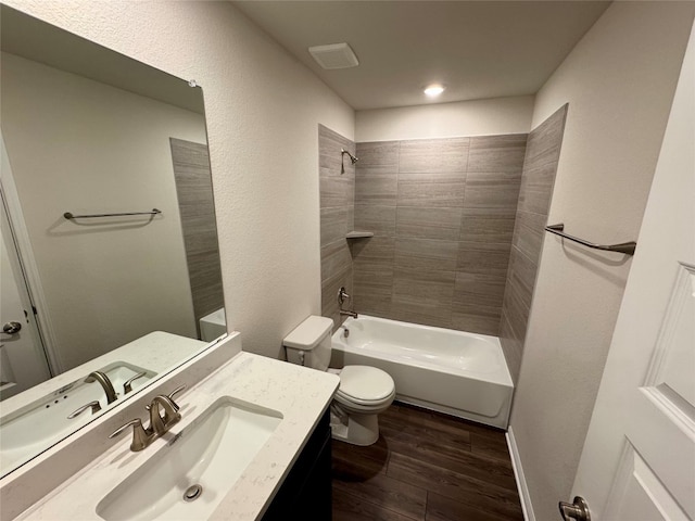 full bathroom with toilet, tiled shower / bath, hardwood / wood-style flooring, and vanity