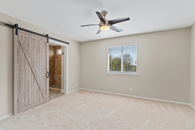 unfurnished room with a barn door, light carpet, and ceiling fan