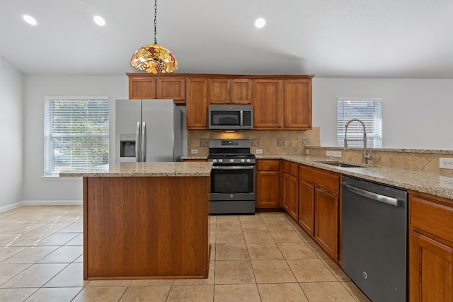 kitchen featuring appliances with stainless steel finishes, sink, decorative light fixtures, light stone counters, and decorative backsplash