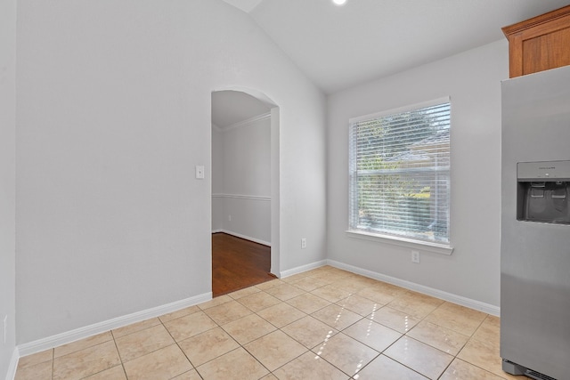 empty room featuring light tile patterned floors, crown molding, and vaulted ceiling