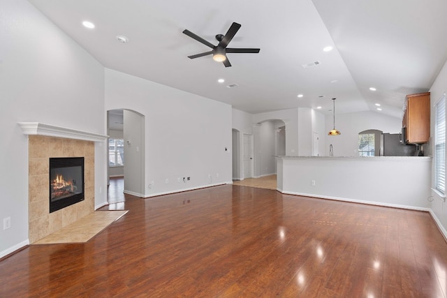 unfurnished living room with ceiling fan, lofted ceiling, dark hardwood / wood-style flooring, and a fireplace