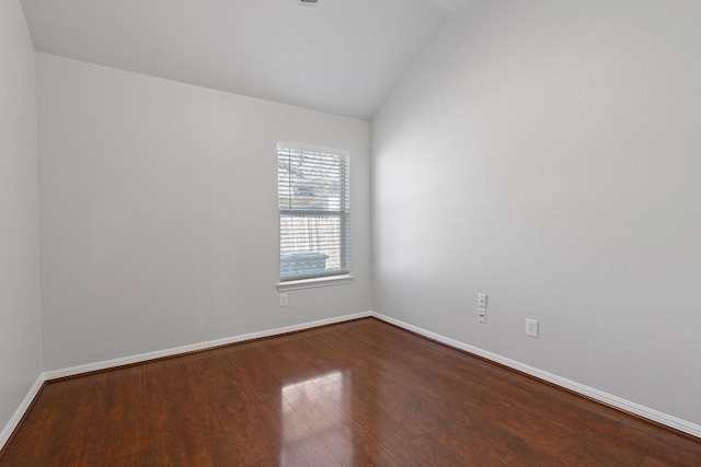 spare room featuring wood-type flooring and vaulted ceiling