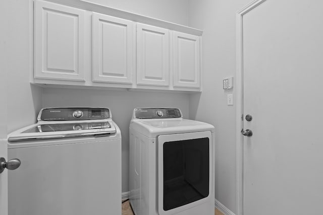 clothes washing area featuring washing machine and clothes dryer and cabinets